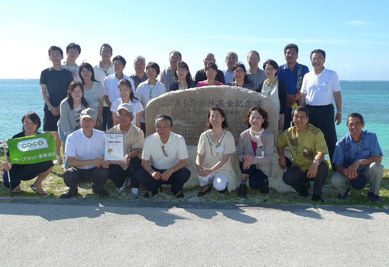 今回の視察参加者と伊平屋島の皆さん。コープネット美ら島応援基金記念碑の前で