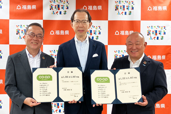 福島県の内堀雅雄知事（右）に目録を渡す、熊﨑伸代表理事理事長