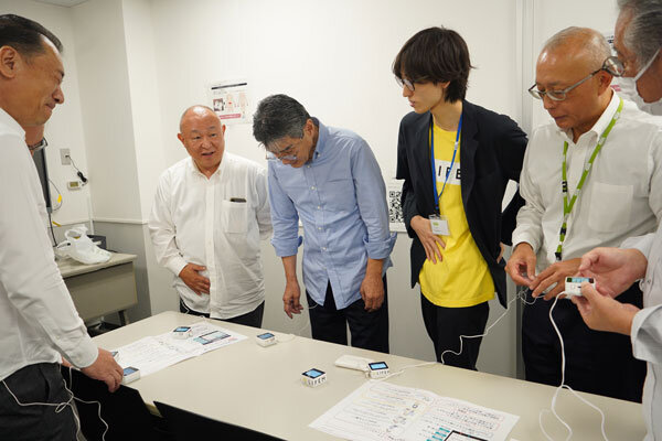 スタッフ（右から3人目）の指導のもと生理痛を疑似体験するコープデリ連合会の理事（左から2人目が熊﨑理事長）